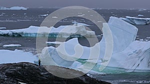 A tourist stands amidst floating icebergs