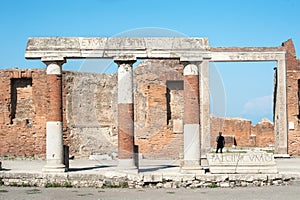 A tourist stands in the doorway of the Building of Eumachia, Pompeii, Italy