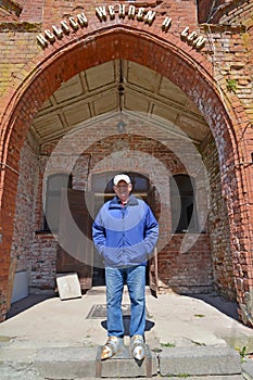 A tourist stands in foot knight`s armor against the background of an arched portal. Shaaken Castle, XIII century. Kaliningrad