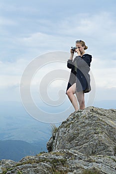 Tourist stands on a rock over a cliff in the Carpathians and photographs