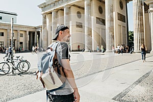 A tourist or a student with a backpack near the Brandenburg Gate in Berlin in Germany, looks at the sights.