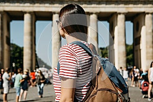 A tourist or a student with a backpack near the Brandenburg Gate in Berlin in Germany, looks at the sights.