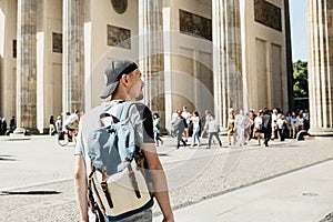 A tourist or a student with a backpack near the Brandenburg Gate in Berlin in Germany, looks at the sights.