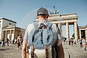 A tourist or a student with a backpack near the Brandenburg Gate in Berlin in Germany, looks at the sights.