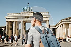 A tourist or a student with a backpack near the Brandenburg Gate in Berlin in Germany, looks at the sights.