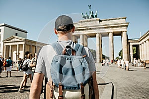 A tourist or a student with a backpack near the Brandenburg Gate in Berlin in Germany, looks at the sights.