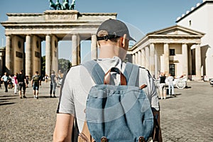 A tourist or a student with a backpack near the Brandenburg Gate in Berlin in Germany, looks at the sights.