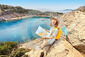 Tourist student with map and greek flag standing on top of the hill at background of the inspirational blue lagoon bay. Solo
