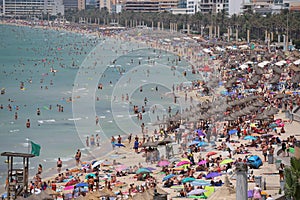 Tourist sunbathe or bath on the sea in crowded El Arenal beach in Mallorca