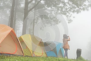 Tourist take photo near tent in mist & fog. camping in forest. p