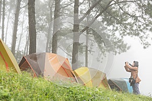 Tourist take photo near tent in mist & fog. camping in forest. p