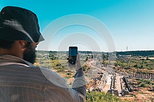 A tourist takes a photo with his phone of the ancient city of Perge from above.