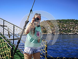 A tourist takes photographs during a Mediterranean cruise off the coast of Alanya, Turkey. A young adult girl holding a camera in