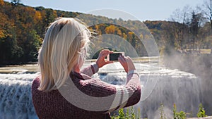 A tourist takes pictures of a beautiful waterfall in Letchworth State Park.