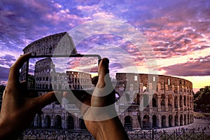 Tourist taking photo of Colosseum Coliseum in Rome at sunset against purple cloudy sky, Italy. Roman oval amphitheater