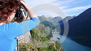 Tourist taking photo of fjord landscape, Norway