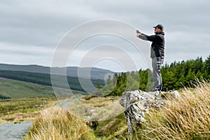 Tourist taking a photo at Glengesh Pass, mountain pass road in west Donegal between the heritage town of Ardara and the lovely