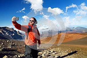 Tourist taking a photo of himself in Haleakala volcano crater on the Sliding Sands trail, Maui, Hawaii