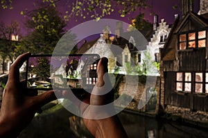 Tourist taking photo of historic buildings and canal in Bruges, Belgium. View of of photo of Bonifacius Bridge and medieaval