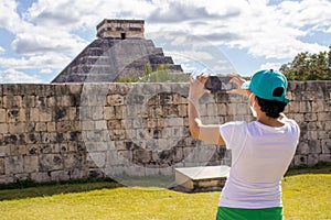 Tourist taking a photo at the Mayan pyramid temple of Kukulkan in Chichen Itza, the famous feathered serpent god of the Mayas photo