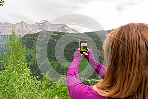 Tourist taking photo of mountains with phone at Glacier National Park