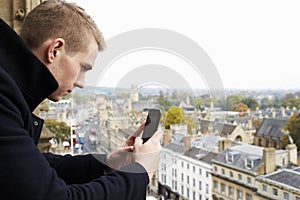Tourist Taking Photo Of Oxford Skyline On Mobile Phone