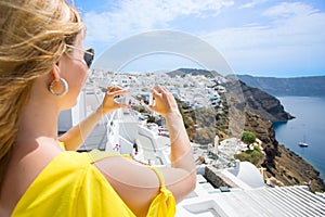 Tourist taking photo of Santorini with mobile phone