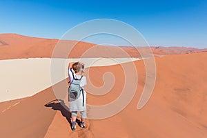 Tourist taking photo at Sossusvlei, Namibia. Scenic sand dunes, Namib desert, Namib Naukluft National Park, travel adventure in Af
