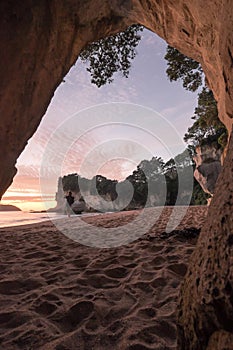 Tourist taking a photograph at Cathedral Cove, Coromandel Peninsula, at sunrise