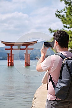 Tourist taking photos of Itsukushima Jinja Otorii on the sea of Miyajima, Japan.