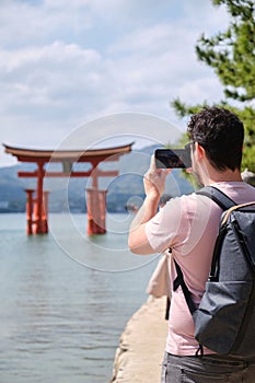 Tourist taking photos of Itsukushima Jinja Otorii on the sea of Miyajima, Japan. photo