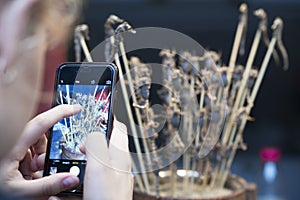 A tourist taking a picture of fried scorpions and seahorses on sticks in Wangfujing street with a smartphone in Beijing, CHina