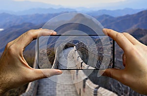 Tourist taking a picture with a mobile phone at the great wall in China