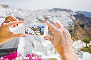 Tourist taking picture of Santorini with mobile phone