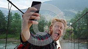 Tourist taking selfie smartphone camera closeup. Guy making funny face on nature