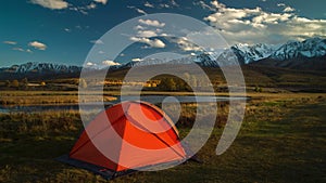 Tourist tent in camp among alpine meadows in the mountains at sunset.