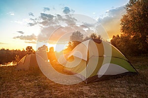 Tourist tents at riverbank in forest in summer morning photo