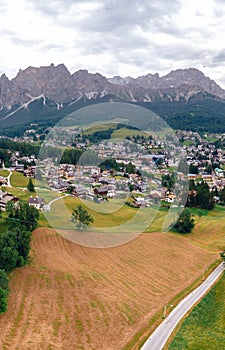 Tourist town Cortina d`Ampezzo, panoramic view with alpine green landscape and massive Dolomites Alps. View of houses and hotels,