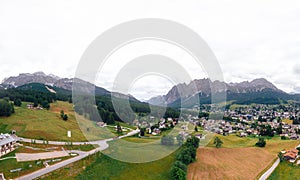 Tourist town Cortina d`Ampezzo, panoramic view with alpine green landscape and massive Dolomites Alps. View of houses and hotels,