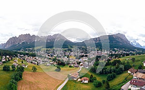 Tourist town Cortina d`Ampezzo, panoramic view with alpine green landscape and massive Dolomites Alps. View of houses and hotels,