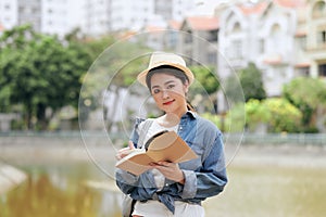 Tourist with travel guide book. Young woman traveler smiling happy