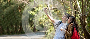 Tourist and traveler asian couple backpack enjoy happy take a photo selfie in the jungle forest nature park