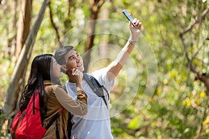 Tourist and traveler asian couple backpack enjoy happy take a photo selfie in the jungle forest nature park . Traveler going campi