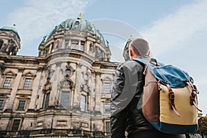 A tourist or traveler with a backpack looks at a tourist attraction in Berlin called Berliner Dom.