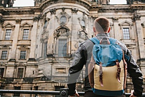 A tourist or traveler with a backpack looks at a tourist attraction in Berlin called Berliner Dom.
