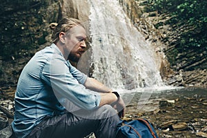 Tourist Traveler With Backpack Sitting On Rocks Near Waterfall Trek Hiking Destination Experience Lifestyle Concept