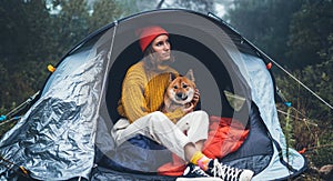 Tourist traveler in camp tent hugging red shiba inu on background froggy rain forest, hiker woman with puppy dog in mist nature