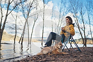 Tourist traveler girl leisure drink tea together dog on background mountain, puppy pet woman rest on lake shore nature trip