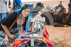 Tourist traveler girl looking sad for the camels used in Morocco for desert tours. Anti animal abuse in tourism concept
