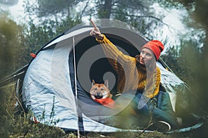 Tourist traveler hugging red shiba inu in camp tent on background froggy rain forest, happy hiker woman with puppy dog in mist